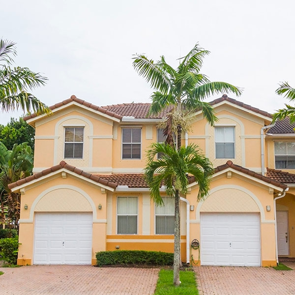 House with garage doors and tree in front